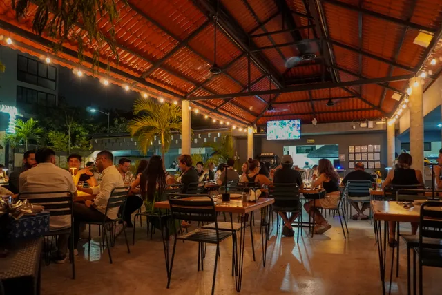 Comensales y mesas bajo las luces cálidas de Criollo Restó